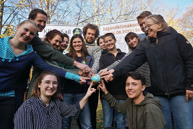 Gruppenfoto mit Klimateamer*innen, die eine Weltkugel in ihrer Mitte halten.