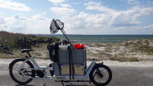 Ein E-Lastenrad, voll beladen steht am Strand.