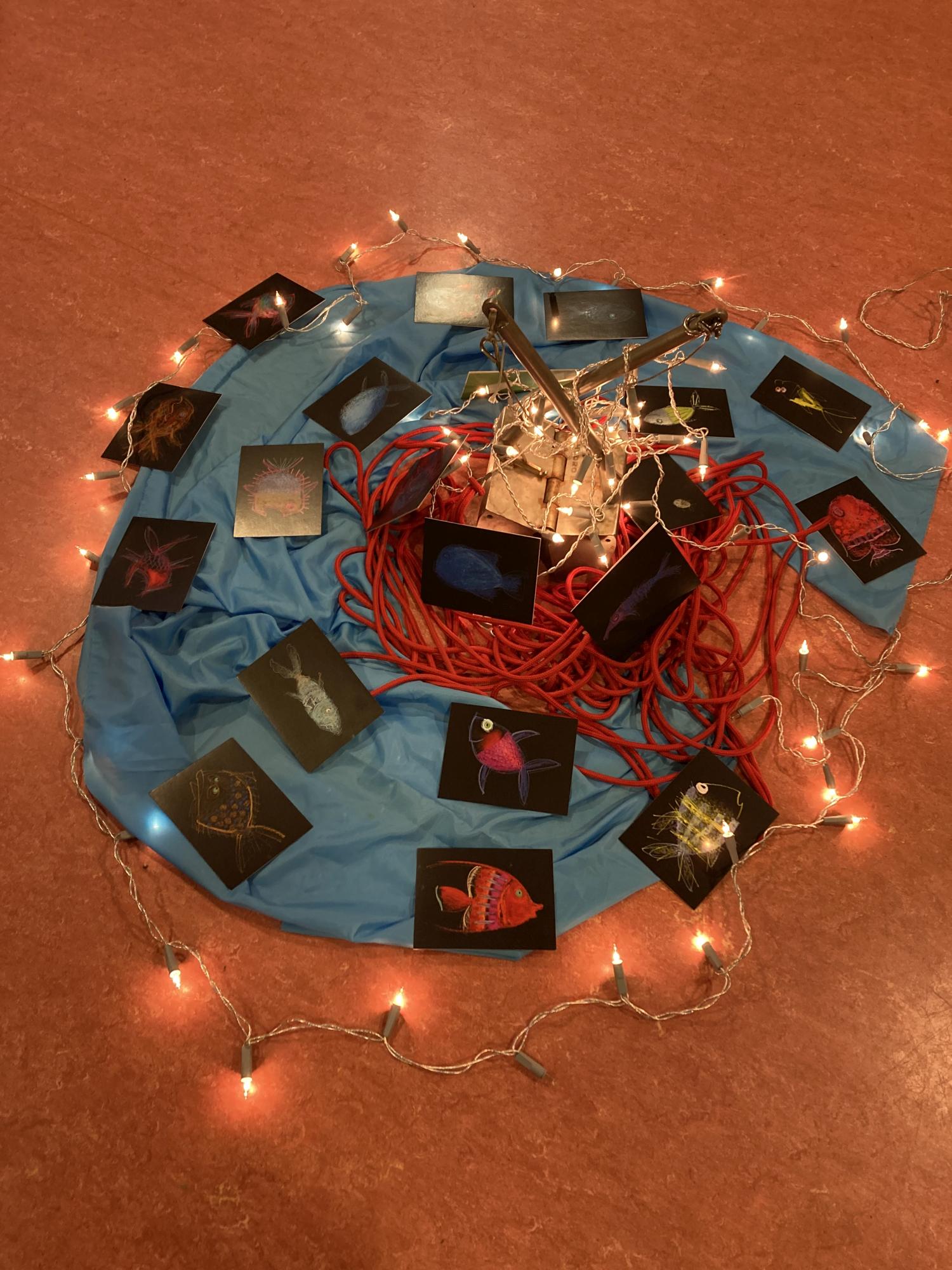 Eine gestaltete Mitte aus Lichterketten, Bildkarten mit Fischen und einem Bodengreifer.