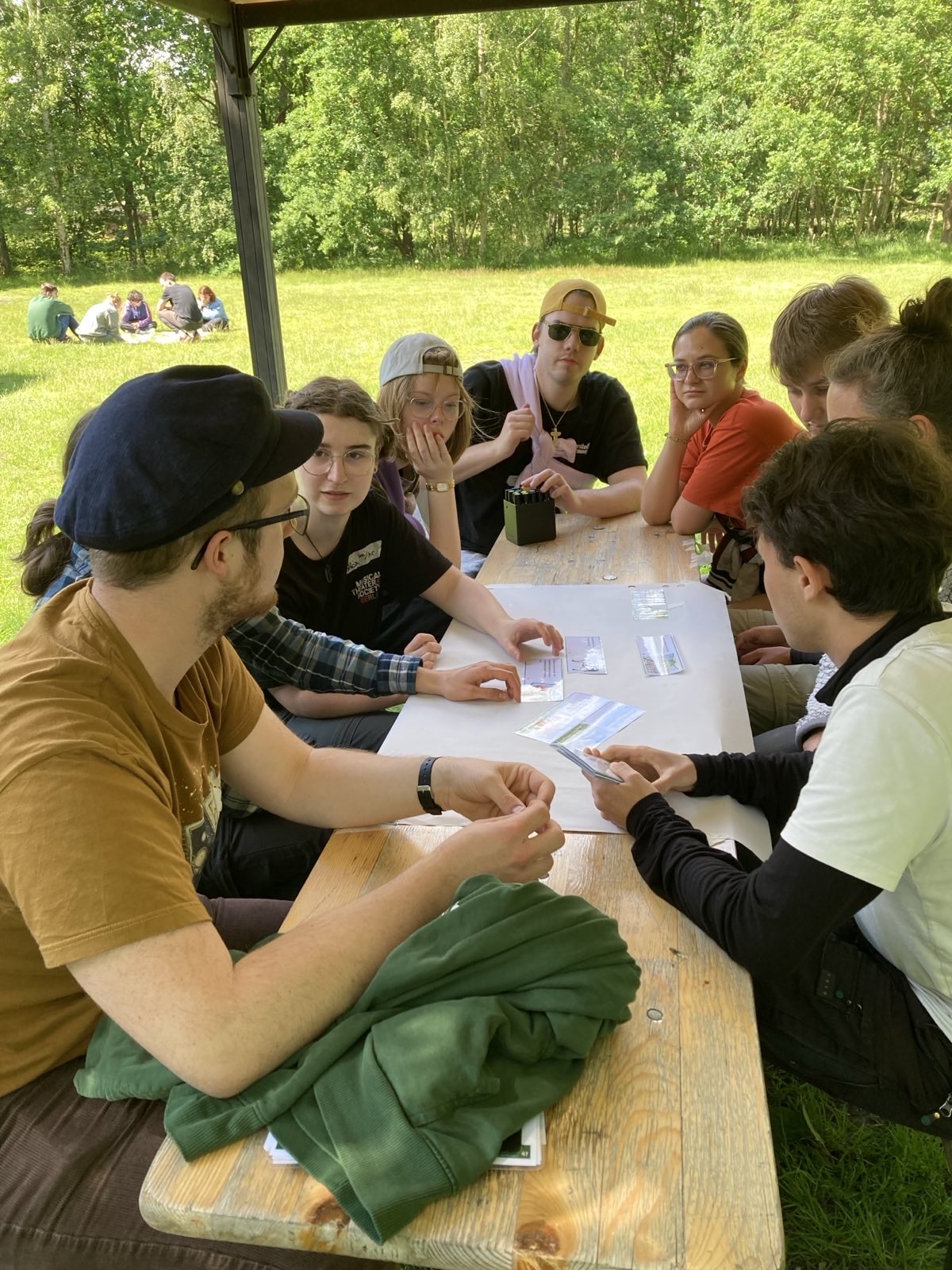 Einige junge Menschen sitzen um ein Flipchart und scheinen zu diskutieren und zu notieren.